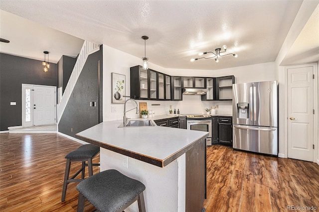 kitchen featuring kitchen peninsula, a breakfast bar area, appliances with stainless steel finishes, decorative light fixtures, and sink