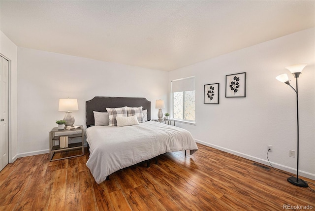 bedroom featuring a textured ceiling and dark hardwood / wood-style floors