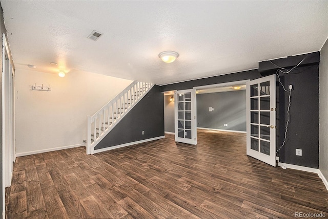 unfurnished living room with a textured ceiling, dark hardwood / wood-style flooring, and french doors