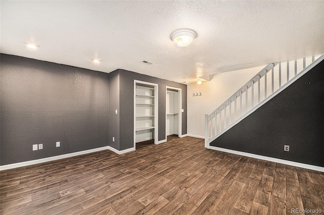 unfurnished room with a textured ceiling, dark wood-type flooring, and built in features