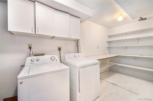 clothes washing area featuring washer and clothes dryer and cabinets