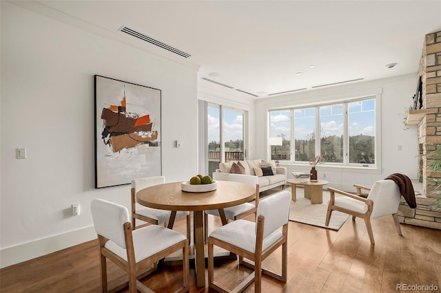 dining space with light wood-type flooring, visible vents, and baseboards