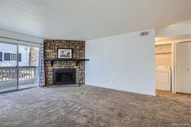 unfurnished living room with visible vents, washer / clothes dryer, a textured ceiling, a stone fireplace, and carpet floors