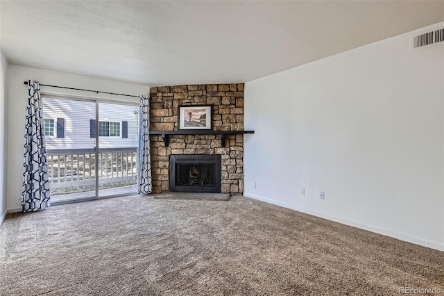 unfurnished living room with baseboards, visible vents, a textured ceiling, a stone fireplace, and carpet floors