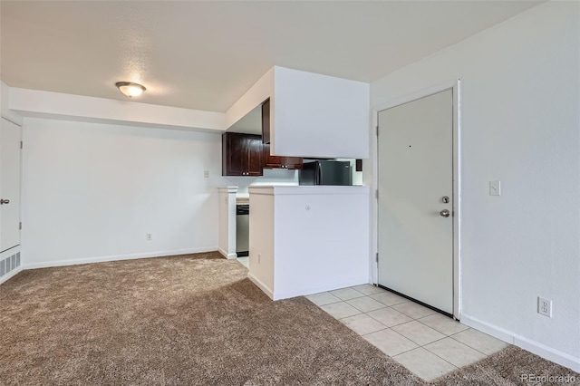 kitchen featuring light carpet, light tile patterned floors, refrigerator, light countertops, and dark brown cabinets