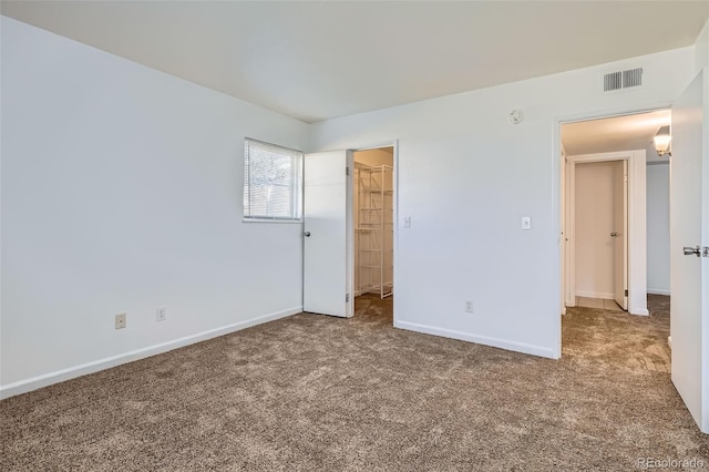 unfurnished bedroom featuring baseboards, visible vents, a walk in closet, carpet flooring, and a closet