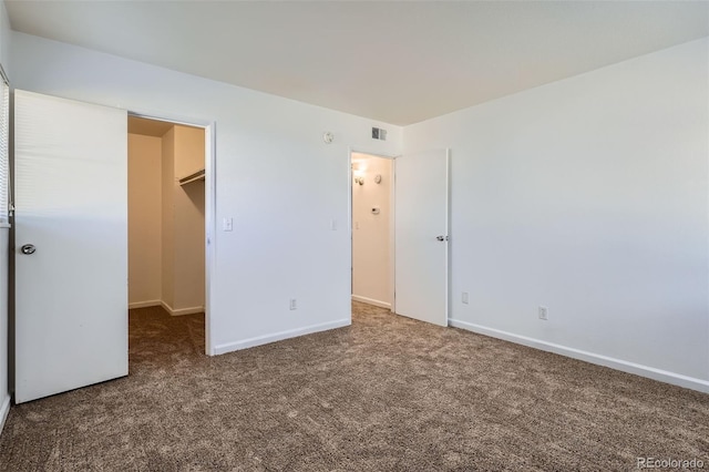 unfurnished bedroom with carpet floors, visible vents, a spacious closet, and baseboards