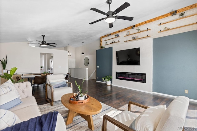 living area featuring ceiling fan, a glass covered fireplace, wood finished floors, and baseboards