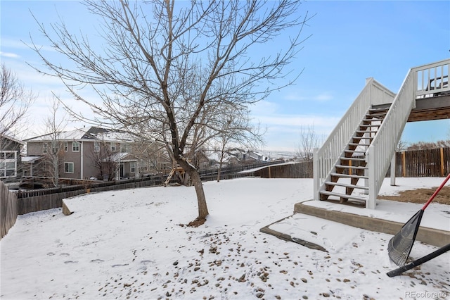 yard layered in snow with a fenced backyard, a residential view, and stairway