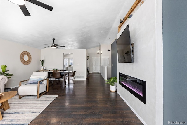 living area featuring baseboards, ceiling fan with notable chandelier, wood finished floors, and a glass covered fireplace