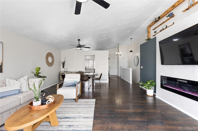 living room with baseboards, ceiling fan with notable chandelier, wood finished floors, and a glass covered fireplace