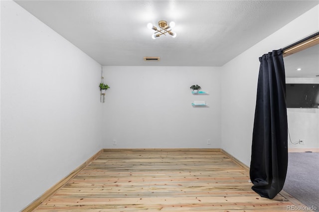 unfurnished room featuring visible vents, hardwood / wood-style flooring, and baseboards