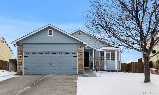 single story home with a garage, stone siding, driveway, and fence