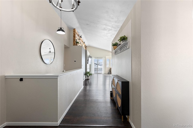 hallway featuring vaulted ceiling, a textured wall, dark wood-style flooring, and baseboards