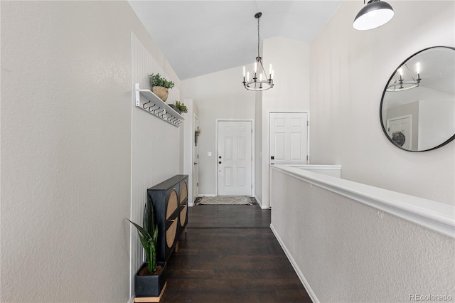 corridor with dark wood-type flooring, a chandelier, vaulted ceiling, and baseboards