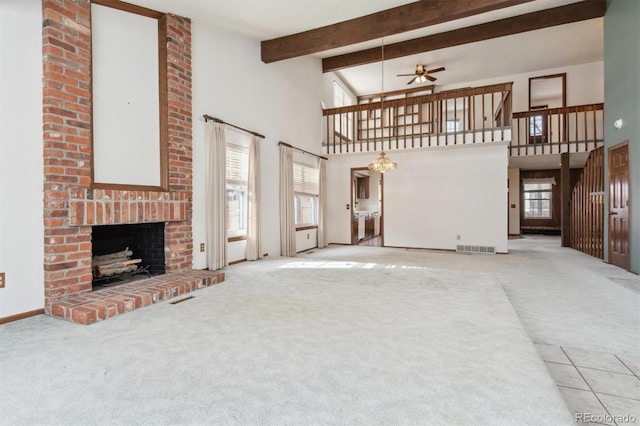 carpeted living room with a towering ceiling, a fireplace, ceiling fan, and a healthy amount of sunlight