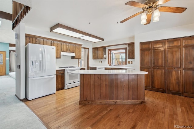 kitchen with white appliances, a center island, ceiling fan, and light hardwood / wood-style flooring