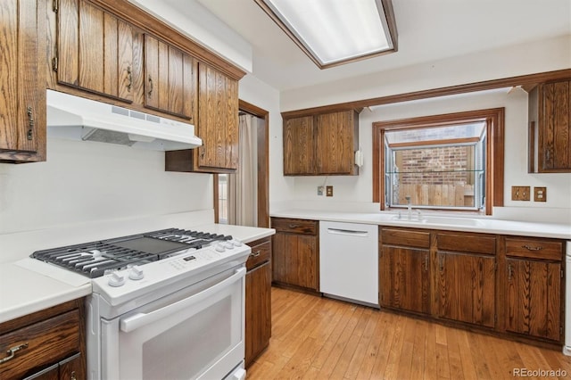 kitchen with white appliances, light wood-type flooring, and sink