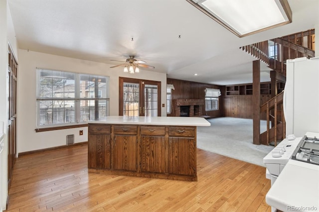 kitchen featuring a fireplace, ceiling fan, light hardwood / wood-style flooring, and a center island