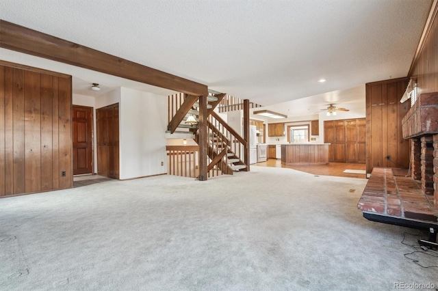 unfurnished living room featuring light colored carpet, wooden walls, and beamed ceiling