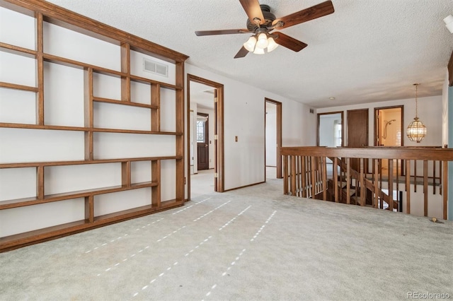 empty room featuring a textured ceiling, light carpet, and ceiling fan