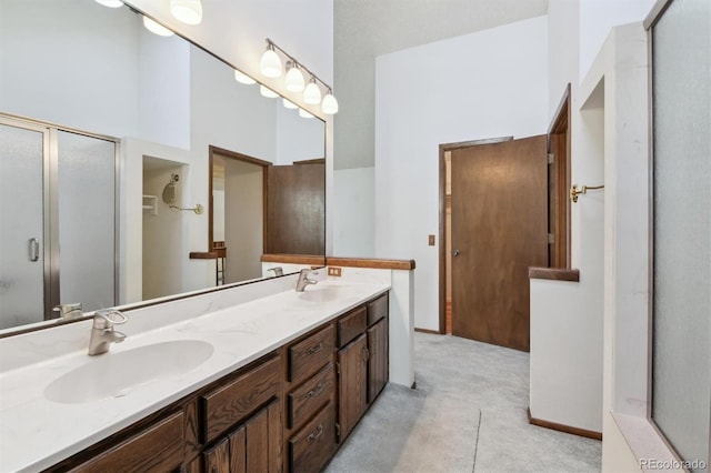 bathroom featuring a high ceiling, vanity, and a shower with shower door