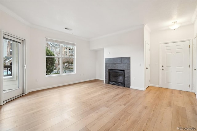 unfurnished living room with visible vents, light wood finished floors, crown molding, and a fireplace