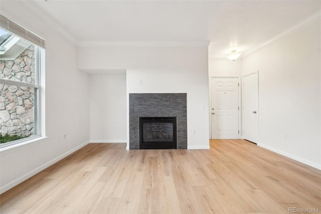 unfurnished living room featuring crown molding, light wood finished floors, baseboards, and a tile fireplace