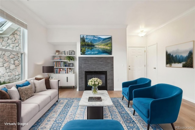 living area featuring crown molding, wood finished floors, and a tile fireplace