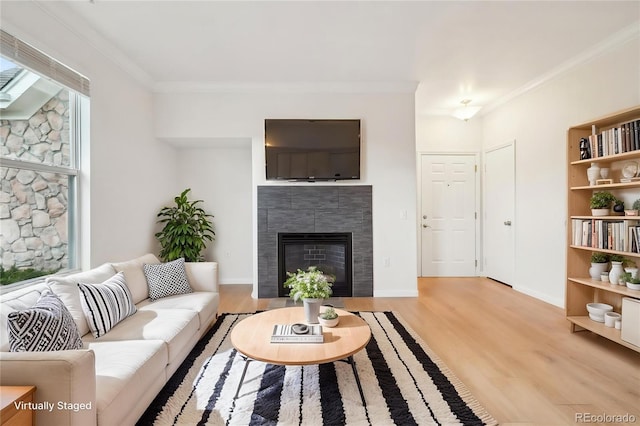 living area featuring crown molding, a tile fireplace, and light wood-type flooring