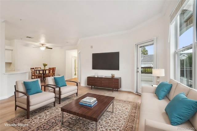 living room with crown molding, visible vents, baseboards, light wood-type flooring, and a ceiling fan