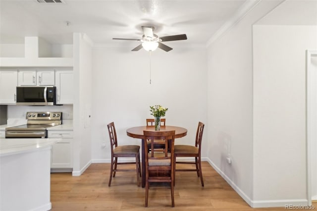dining room featuring a ceiling fan, visible vents, crown molding, light wood-type flooring, and baseboards