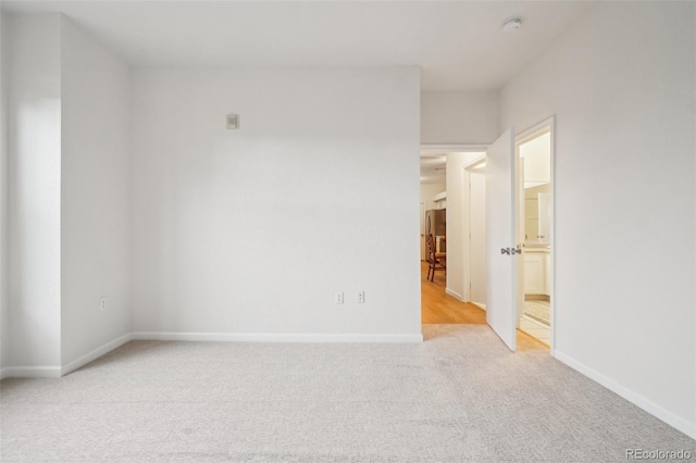 empty room with baseboards and light carpet