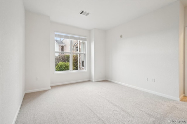 empty room featuring carpet floors, baseboards, and visible vents