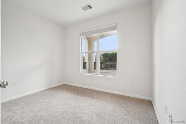 carpeted spare room featuring baseboards and visible vents