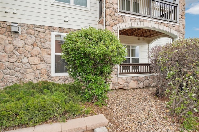 doorway to property with a balcony and stone siding