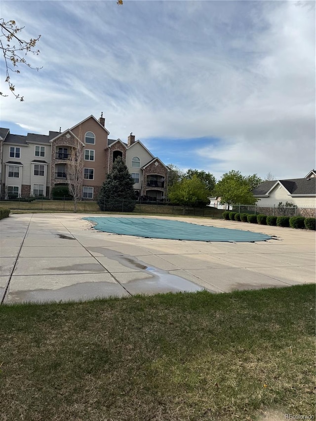pool with a patio area, fence, and a yard