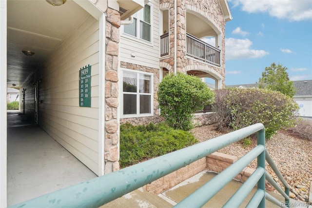 view of side of home featuring a balcony and stone siding