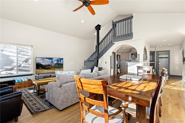 dining area with ceiling fan, high vaulted ceiling, and light hardwood / wood-style floors