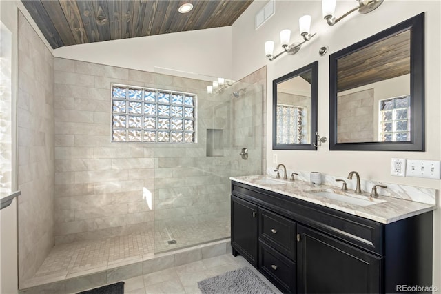 bathroom with a healthy amount of sunlight, vanity, vaulted ceiling, and tiled shower