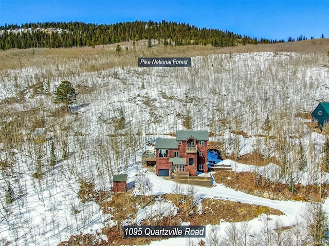 snowy aerial view featuring a wooded view