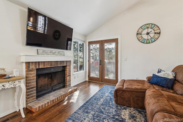 living room with visible vents, wood finished floors, french doors, a brick fireplace, and vaulted ceiling