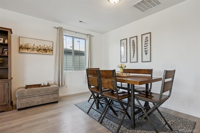 dining room featuring light wood-style floors, baseboards, and visible vents