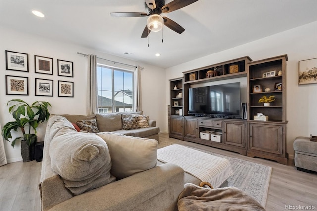 living room featuring ceiling fan, light wood-style flooring, and baseboards