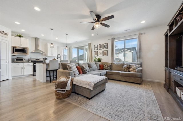 living room featuring a ceiling fan, recessed lighting, visible vents, and light wood-style flooring