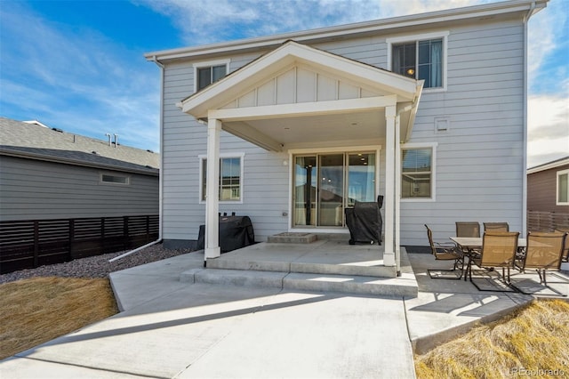 back of property featuring board and batten siding, a patio, and fence