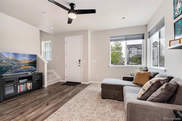 living room featuring dark wood-type flooring and ceiling fan