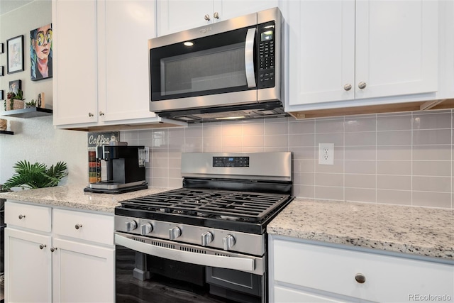 kitchen featuring white cabinetry, light stone countertops, decorative backsplash, and stainless steel appliances