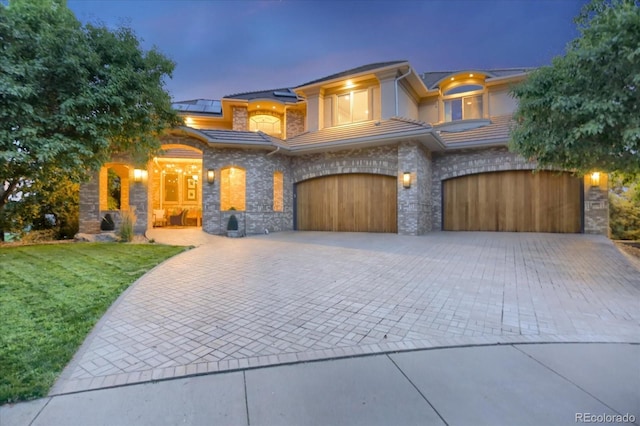 2421 Ranch Reserve Rdg, Denver, CO 80234 - view of front of property with stone siding, a garage, solar panels, decorative driveway, and a front yard
