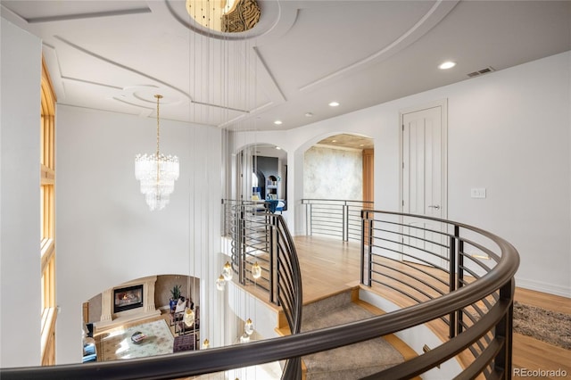 2421 Ranch Reserve Rdg, Denver, CO 80234 - stairway with wood finished floors, a chandelier, recessed lighting, arched walkways, and a lit fireplace